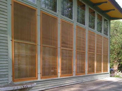 There is a wooden house whose windows are installed with copper insect screens.