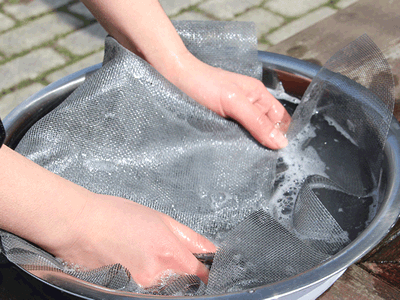 A piece of fiberglass window screen is washed on a basin.