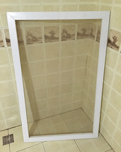 There is an insect screens which is removed from a window and is placed in the bathroom.
