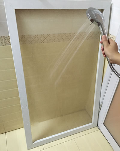 An insect screen is rinsed by a hand-held shower in the bathroom.