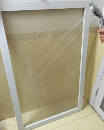 A hand-held shower is watering the screen in order to wash form down.